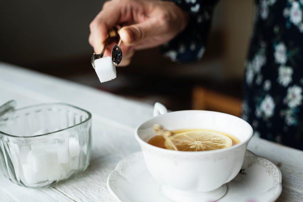 Woman trying to put sugar into ginger tea.|How to stop facial hair growth due to PCOS?